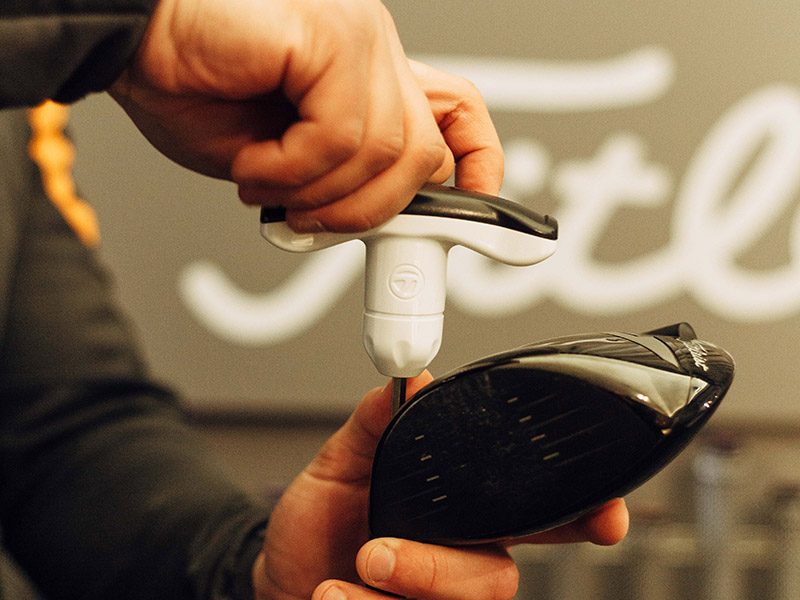 A golf professional fitting equipment